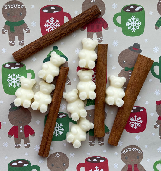 Decorative cinnamon sticks with white candy pieces on a festive background with gingerbread men and hot chocolate mugs.